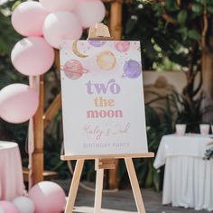 there is a sign that says two the moon on it and balloons in the background