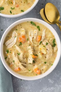 two bowls of chicken and dumpling soup with spoons next to it on a gray surface