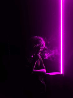 a man standing in front of a purple light holding a cell phone to his ear