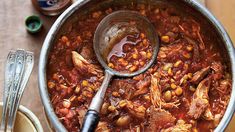 a pot filled with meat and beans on top of a wooden table