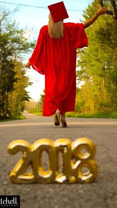 a woman in a graduation gown is walking down the street with her arms out to the side