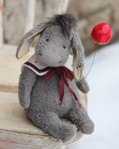 a gray stuffed animal sitting on top of a wooden bench next to a red ball