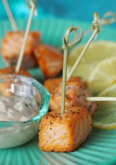 salmon skewers with ranch dip and lemon wedges on a blue platter