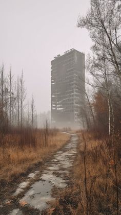 a very tall building sitting in the middle of a field next to a dirt road