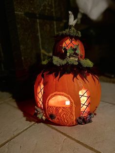 two carved pumpkins sitting on the ground with candles in them and one is lit