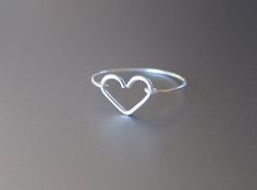 a heart shaped ring sitting on top of a gray surface with the word love written in it