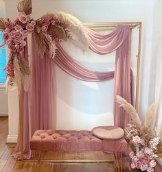 a pink canopy bed decorated with flowers and feathers