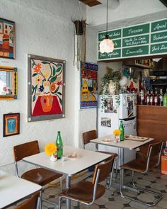 the interior of a restaurant with tables, chairs and pictures on the wall above them