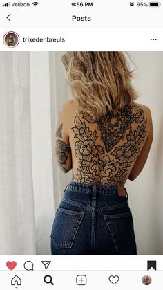 a woman with tattoos on her back standing next to a window