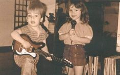 two young children standing next to each other while holding guitars and singing into microphones