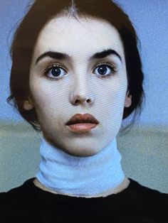 a close up of a person wearing a turtle neck shirt and looking at the camera