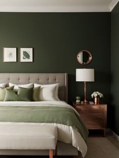 a bedroom with green walls and white linens on the bed, along with two framed pictures