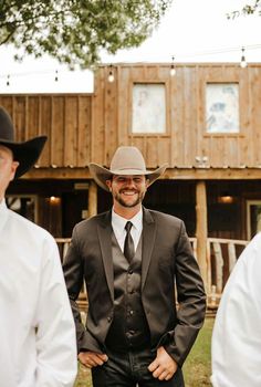 a man in a suit and tie standing next to another man wearing a cowboy hat