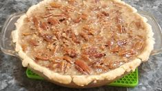 a pecan pie sitting on top of a green plastic tray next to a gray counter