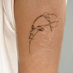 a woman's arm with a tattoo on it that has a drawing of a face