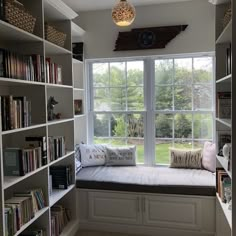 a window seat in the corner of a room with bookshelves full of books