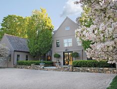 a large gray house surrounded by trees and flowers