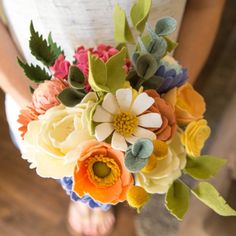 the bride's bouquet is made with felt flowers and greenery for an elegant touch