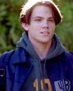 a young man in a blue hoodie is looking at the camera