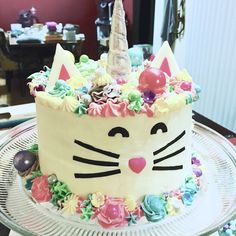 a cake decorated with flowers and a cat's face is on a glass platter