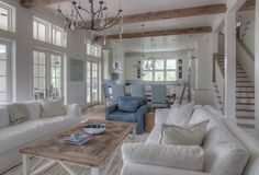 a living room filled with furniture and a chandelier above a wooden coffee table