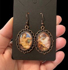 a pair of earrings with an image of a woman holding a baby in her lap