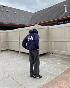 a man standing in front of a building wearing a blue hoodie with the words books here written on it