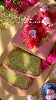 two slices of cake with strawberries and flowers on them sitting on a table next to pink flowers