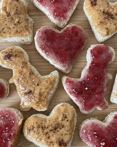 heart shaped cookies with peanut butter and jelly toppings arranged on a wooden table top