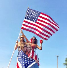 three women are holding an american flag and posing for the camera