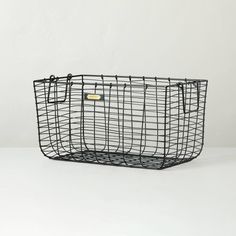 a black wire basket sitting on top of a white table