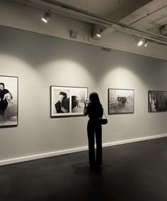 a woman is looking at pictures on the wall in an art gallery with black and white photos