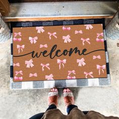 someone standing in front of a welcome mat with pink bows on it that says, welcome