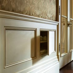 an empty room with wooden floors and white walls, painted in gold paint on the wall