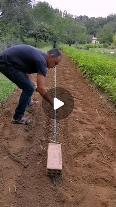 a man bending over to look at an object in the dirt