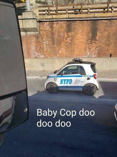 a baby cop car driving down a street next to a brick wall with the caption, i can hear this picture