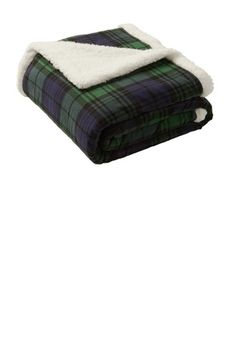 a blanket that is folded up on top of a white surface with a black and green plaid