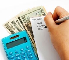 a person holding a calculator next to a stack of money and a note