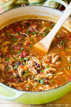 a green pot filled with chicken tortilla soup on top of a wooden table