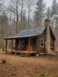 a small cabin in the woods with a stone chimney