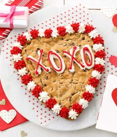 a heart shaped cookie cake with the word love spelled in red and white icing