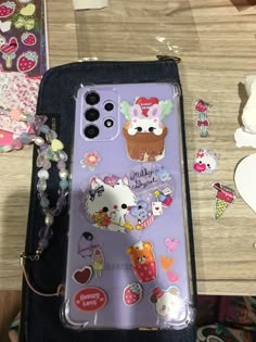 an iphone case with stickers on it sitting on a table next to other items