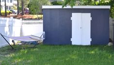 a hammock is sitting in the grass next to a shed with a door