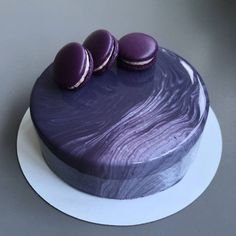 a purple cake with three macaroons on top