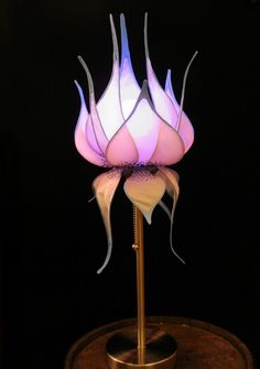 a lamp that is sitting on top of a wooden stand with a flower in the center