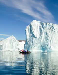 two people in a small boat near an iceberg