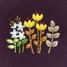 embroidered flowers on purple fabric with green leaves