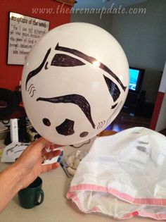 a person holding a white balloon with a drawing on it's face in the shape of a storm trooper