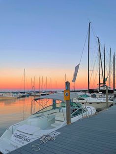 several boats docked at a pier with the sun setting in the background