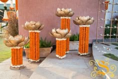 three tall vases with flowers in them sitting on the side of a building next to a potted plant